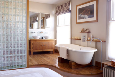 Exempel på ett mellanstort modernt en-suite badrum, med ett fristående handfat, släta luckor, skåp i mellenmörkt trä, ett fristående badkar, beige väggar och mellanmörkt trägolv