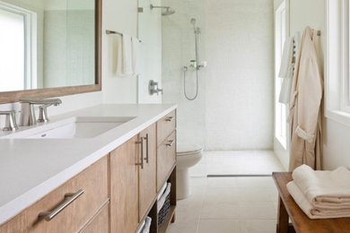Example of a large trendy 3/4 white tile porcelain tile and white floor bathroom design in Atlanta with flat-panel cabinets, light wood cabinets, white walls, an undermount sink and solid surface countertops