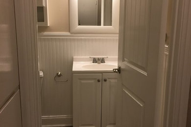 Example of a small classic 3/4 ceramic tile and brown floor bathroom design in San Francisco with raised-panel cabinets, white cabinets, a two-piece toilet, beige walls, an integrated sink and quartz countertops