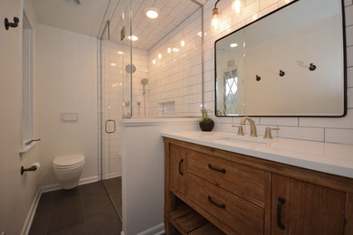 Mid-sized elegant white tile and subway tile cement tile floor and gray floor corner shower photo in Other with flat-panel cabinets, medium tone wood cabinets, a wall-mount toilet, white walls, an undermount sink, quartz countertops, a hinged shower door and white countertops