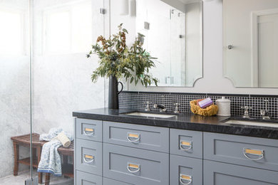 This is an example of a large traditional ensuite bathroom in Los Angeles with shaker cabinets, grey cabinets, a one-piece toilet, black tiles, stone tiles, white walls, marble flooring, a submerged sink, marble worktops, an alcove shower and a hinged door.