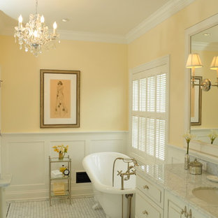 Photo of a mid-sized traditional bathroom in San Francisco with an undermount sink, raised-panel cabinets, white cabinets, marble benchtops, a claw-foot tub, a two-piece toilet, white tile, stone tile, yellow walls and marble floors.