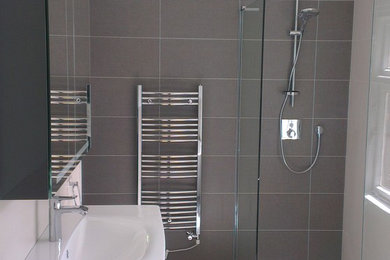 Photo of a contemporary family bathroom in West Midlands with black cabinets, a freestanding bath, a walk-in shower, grey tiles, ceramic tiles, grey walls, ceramic flooring and a wall-mounted sink.