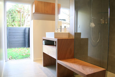Doorless shower - contemporary gray tile and porcelain tile porcelain tile doorless shower idea in Auckland with a vessel sink, flat-panel cabinets, medium tone wood cabinets, wood countertops, a wall-mount toilet and white walls