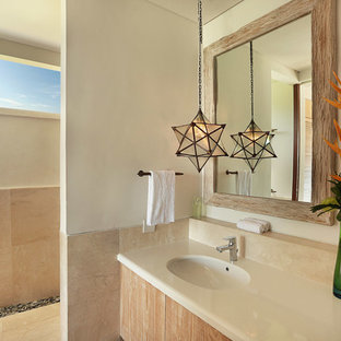 Idee per una stanza da bagno tropicale di medie dimensioni con ante lisce, ante con finitura invecchiata, doccia aperta, piastrelle beige, piastrelle di marmo, pareti beige, pavimento in marmo, lavabo da incasso, pavimento beige e doccia aperta