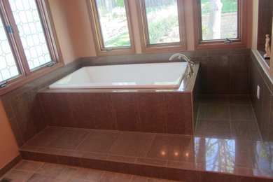 Diseño de cuarto de baño clásico con bañera esquinera, baldosas y/o azulejos marrones, suelo de baldosas de cerámica y aseo y ducha