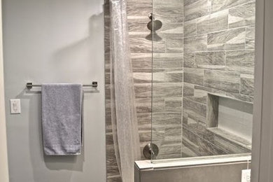 Foto på ett mellanstort vintage badrum, med släta luckor, gula skåp, ett badkar i en alkov, en dusch/badkar-kombination, beige kakel, brun kakel, porslinskakel, grå väggar, klinkergolv i porslin, ett undermonterad handfat och marmorbänkskiva