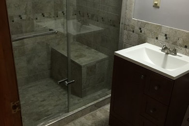Example of a small classic 3/4 ceramic tile and gray tile ceramic tile and gray floor alcove shower design in New York with dark wood cabinets, gray walls, a drop-in sink, a hinged shower door, shaker cabinets, a two-piece toilet and solid surface countertops
