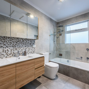 Inspiration for a mid-sized contemporary bathroom in Melbourne with a drop-in tub, a shower/bathtub combo, multi-coloured tile, grey walls, ceramic floors, marble benchtops, grey floor, white benchtops, flat-panel cabinets, medium wood cabinets, mosaic tile, an integrated sink and an open shower.