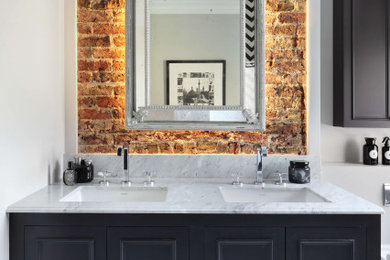 This is an example of a medium sized contemporary ensuite bathroom in London with white cabinets, a wall mounted toilet, white tiles, marble tiles, white walls, ceramic flooring, a submerged sink, marble worktops, white floors, white worktops, double sinks and a built in vanity unit.