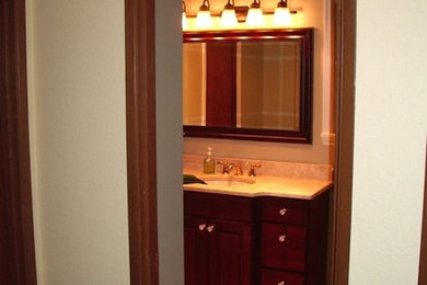 Aménagement d'une salle de bain en bois foncé avec un lavabo posé et un placard à porte affleurante.