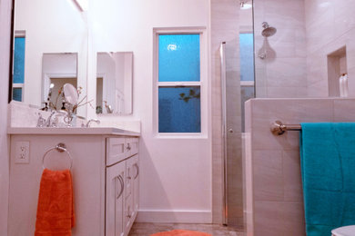 Example of a mid-sized transitional master gray tile and porcelain tile porcelain tile and beige floor walk-in shower design in Los Angeles with shaker cabinets, white cabinets, white walls, an undermount sink, quartz countertops, a hinged shower door and white countertops