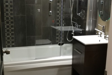Small urban master gray tile and pebble tile porcelain tile and multicolored floor tub/shower combo photo in Los Angeles with flat-panel cabinets, dark wood cabinets, a hot tub, a two-piece toilet, multicolored walls, a console sink, a hinged shower door and white countertops