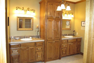 Example of a master porcelain tile bathroom design in Kansas City with a drop-in sink, raised-panel cabinets, light wood cabinets, granite countertops and green walls