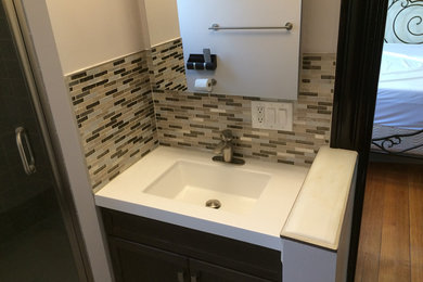 Modernes Badezimmer mit Stäbchenfliesen, beiger Wandfarbe, braunem Holzboden, integriertem Waschbecken, Quarzit-Waschtisch und dunklen Holzschränken in Boston