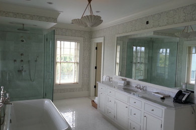 Inspiration for a large transitional master gray tile and stone tile ceramic tile and white floor bathroom remodel in New York with a drop-in sink, flat-panel cabinets, white cabinets, a one-piece toilet, multicolored walls, marble countertops, a hinged shower door and gray countertops