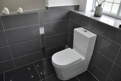 Design ideas for a medium sized modern bathroom in Surrey with a console sink, flat-panel cabinets, white cabinets, a corner shower, a two-piece toilet, grey tiles, porcelain tiles, white walls and porcelain flooring.