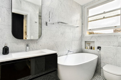 Photo of a small contemporary bathroom in Sydney with distressed cabinets, a freestanding bath, an alcove shower, a wall mounted toilet, multi-coloured tiles, grey walls, mosaic tile flooring and a sliding door.