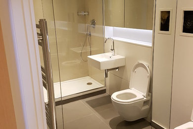 Ejemplo de cuarto de baño infantil contemporáneo de tamaño medio con ducha a ras de suelo, sanitario de pared, baldosas y/o azulejos beige y lavabo suspendido