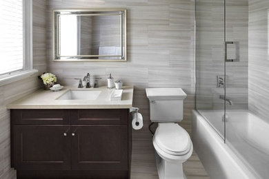 Example of a mid-sized trendy 3/4 beige tile and porcelain tile porcelain tile and beige floor bathroom design in Calgary with shaker cabinets, dark wood cabinets, a two-piece toilet, beige walls, an undermount sink, quartz countertops and a hinged shower door
