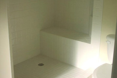 Example of a mid-sized white tile and ceramic tile doorless shower design in Raleigh with a one-piece toilet and yellow walls