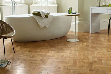 Modelo de cuarto de baño principal actual de tamaño medio con bañera exenta, paredes beige, suelo de madera en tonos medios y suelo marrón