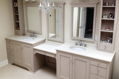 Design ideas for a medium sized traditional ensuite bathroom in New York with recessed-panel cabinets, beige cabinets, beige walls, porcelain flooring, a submerged sink, solid surface worktops and white floors.