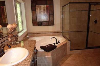 Modelo de cuarto de baño grande con lavabo encastrado, bañera esquinera, ducha esquinera y baldosas y/o azulejos beige