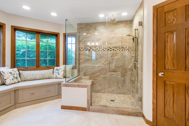 Photo of a large modern ensuite bathroom in Milwaukee with recessed-panel cabinets, medium wood cabinets, a corner shower, a one-piece toilet, beige tiles, porcelain tiles, beige walls, porcelain flooring, quartz worktops, beige floors, a hinged door, beige worktops and a submerged sink.