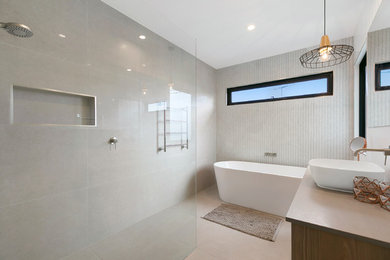 Foto di una stanza da bagno design di medie dimensioni con ante in legno chiaro, vasca freestanding, doccia aperta, piastrelle grigie, piastrelle in pietra, pareti grigie, pavimento in gres porcellanato, top in quarzo composito, pavimento grigio, doccia aperta e top grigio