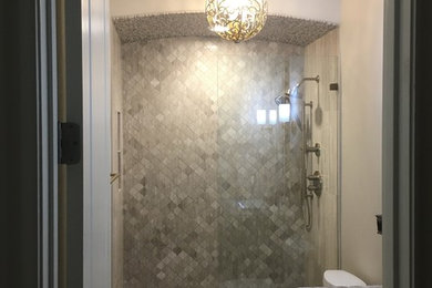 Alcove shower - mid-sized transitional 3/4 gray tile and limestone tile limestone floor alcove shower idea in Austin with recessed-panel cabinets, gray cabinets, a two-piece toilet, gray walls, a drop-in sink and quartz countertops