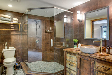 Large transitional brown tile and porcelain tile corner shower photo in Salt Lake City with a vessel sink, medium tone wood cabinets and wood countertops