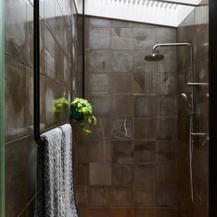 Photo of a mid-sized modern bathroom in Brisbane with an open shower, a wall-mount toilet, gray tile, limestone, grey walls, light hardwood floors and an open shower.