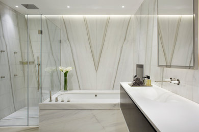 Bild på ett funkis en-suite badrum, med släta luckor, svarta skåp, ett hörnbadkar, en hörndusch, grå kakel, vit kakel, ett integrerad handfat och dusch med gångjärnsdörr