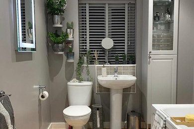 Medium sized contemporary family bathroom in West Midlands with shaker cabinets, grey cabinets, a built-in bath, a shower/bath combination, a one-piece toilet, grey tiles, ceramic tiles, grey walls, vinyl flooring, a built-in sink, tiled worktops, brown floors, a hinged door and grey worktops.