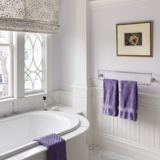 Elegant master white tile drop-in bathtub photo in Boston with white cabinets, marble countertops and purple walls