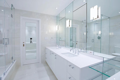 ニューヨークにある中くらいなトランジショナルスタイルのおしゃれなマスターバスルーム (フラットパネル扉のキャビネット、白いキャビネット、置き型浴槽、コーナー設置型シャワー、白い壁、アンダーカウンター洗面器、白い床、開き戸のシャワー) の写真