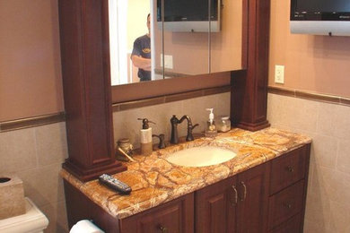 Inspiration for a timeless brown tile bathroom remodel in New York with an undermount sink, raised-panel cabinets, dark wood cabinets and granite countertops
