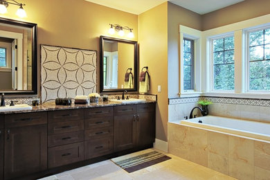 タンパにあるトラディショナルスタイルのおしゃれなマスターバスルーム (オーバーカウンターシンク、落し込みパネル扉のキャビネット、濃色木目調キャビネット、ドロップイン型浴槽、ベージュの壁) の写真