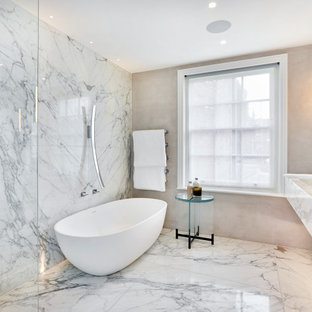 This is an example of a large contemporary ensuite bathroom in London with marble worktops, open cabinets, white cabinets, a freestanding bath, a walk-in shower, grey tiles, beige walls, an integrated sink, grey floors, an open shower and white worktops.