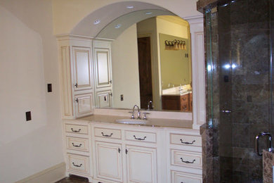 Mid-sized tuscan master brown tile and stone tile dark wood floor and brown floor corner shower photo in Charlotte with raised-panel cabinets, white cabinets, white walls, an undermount sink, quartz countertops and a hinged shower door
