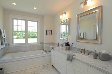 Mid-sized transitional master gray tile and marble tile marble floor and gray floor drop-in bathtub photo in New York with recessed-panel cabinets, white cabinets, white walls, an undermount sink, granite countertops and gray countertops