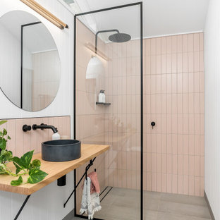 Photo of a mid-sized contemporary 3/4 bathroom in Sydney with a curbless shower, pink tile, a vessel sink, wood benchtops, grey floor, an open shower, beige benchtops, a single vanity and a floating vanity.