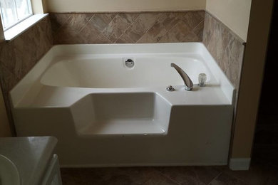 アトランタにあるおしゃれな浴室 (オーバーカウンターシンク、白いキャビネット、人工大理石カウンター、アルコーブ型浴槽、ベージュのタイル、セラミックタイル、ベージュの壁、セラミックタイルの床) の写真