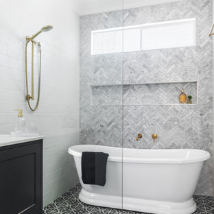Photo of a large traditional master wet room bathroom in Brisbane with recessed-panel cabinets, black cabinets, a freestanding tub, gray tile, multi-coloured floor, an open shower, white benchtops, a niche and a built-in vanity.
