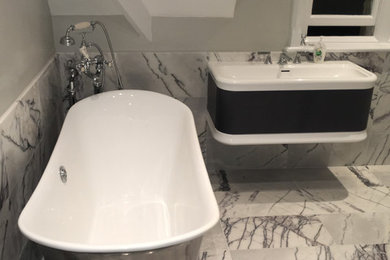 Inspiration for a medium sized contemporary family bathroom in Oxfordshire with a freestanding bath, a wall mounted toilet, marble tiles, grey walls, marble flooring and a wall-mounted sink.