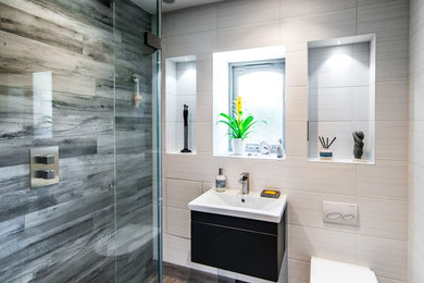 This is an example of a medium sized modern ensuite bathroom in Kent with a walk-in shower, a wall mounted toilet, porcelain tiles, porcelain flooring, a wall-mounted sink and an open shower.