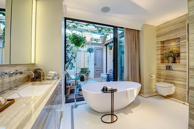 Photo of a large modern ensuite bathroom in London with flat-panel cabinets, green cabinets, a freestanding bath, a double shower, a wall mounted toilet, green tiles, marble tiles, green walls, marble flooring, an integrated sink, marble worktops, white floors, a hinged door and green worktops.