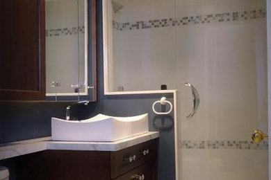 トロントにある小さなトランジショナルスタイルのおしゃれなバスルーム (浴槽なし) (落し込みパネル扉のキャビネット、濃色木目調キャビネット、白いタイル、大理石の洗面台、グレーの洗面カウンター、アルコーブ型シャワー、セラミックタイル、青い壁、ベッセル式洗面器、ベージュの床、開き戸のシャワー) の写真