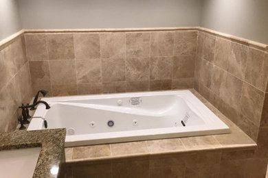 Large classic ensuite bathroom in Kansas City with beaded cabinets, medium wood cabinets, a built-in bath, a double shower, a two-piece toilet, beige tiles, marble tiles, beige walls, marble flooring, a submerged sink, granite worktops, beige floors, an open shower and multi-coloured worktops.